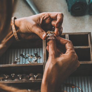 image of a woman putting on 2 hand crafted rings onto her thumb.